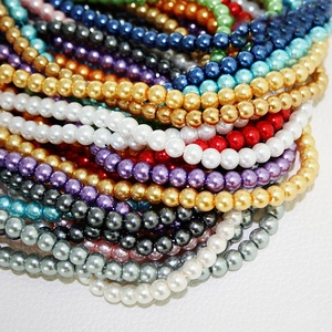 Macro shot of colorful 4-10mm glass pearls for DIY jewelry making stacked on white texture