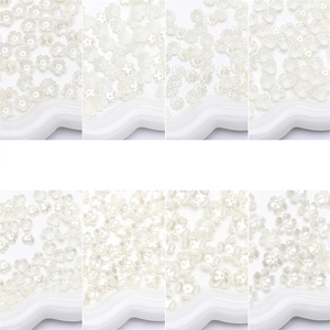 Macro view of 8 different white pearlized resin flower beads for DIY jewelry making crafts