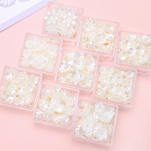 Matrix of white pearlized resin flower beads for DIY jewelry in square storage cases