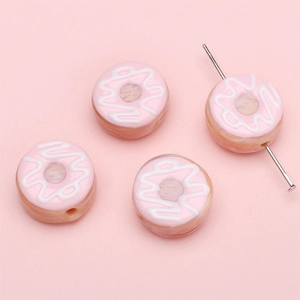 Detaillierte Makroansicht von vier rosa Donut-Glasperlen für DIY-Schmuckherstellung