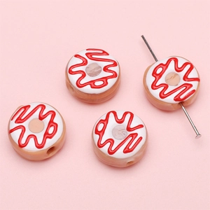 Makro-Detail von handgemachten Donut-Perlen mit cremigen roten Wellenmustern für DIY-Schmuck