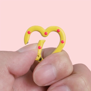 Mousqueton coeur jaune à pois roses avec fermoir à ressort tenu à la main