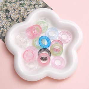 Translucent resin rings with embossed cloud patterns in a white floral ceramic dish