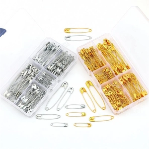 Assorted gold and silver safety pins in a clear organizer box for DIY sewing projects