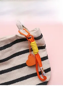 Vue rapprochée d'un porte-clés tressé orange avec breloque cœur sur un sac