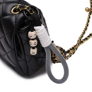 Black quilted leather crossbody bag with creative woven DIY keychain accessory detail