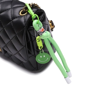 Dettaglio borsa in pelle nera trapuntata con ciondolo a faccina verde neon