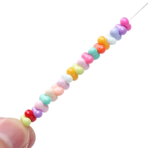 Detalle de cuentas de vidrio coloridas con forma de cacahuete para joyería artesanal DIY