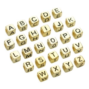 Macro view of 26 golden acrylic cube beads with black engraved letters for DIY jewelry
