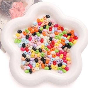 Dettaglio di perle acriliche colorate a forma di arachide in vassoio bianco per gioielli DIY