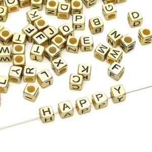 Macro shot of gold square acrylic alphabet beads showing HAPPY word for DIY jewelry making