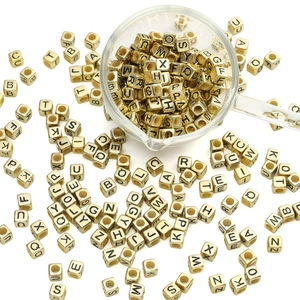 Macro view of 6mm golden cube letter beads with black engravings for DIY jewelry making