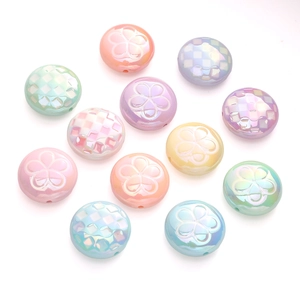 Macro detail of iridescent macaron acrylic beads with floral and grid embossed patterns