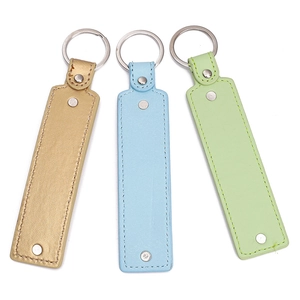 Close-up of three faux leather keychains in gold, light blue, and green with metal rings