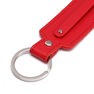 Macro detail of red leather keychain with silver metal ring and reinforced double stitching