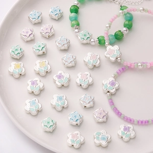 Macro detail of tulip and star enamel flower beads for DIY jewelry making on white ceramic