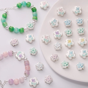 Close-up of matte silver tulip and floral enamel beads for DIY handmade jewelry crafts