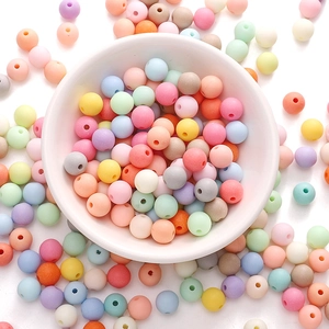 Macro shot of colorful matte acrylic beads for DIY jewelry making in a white bowl