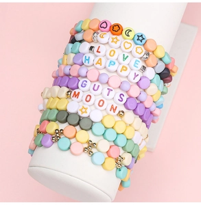 Close-up of pastel acrylic alphabet bead bracelets on a white cylinder jewelry display