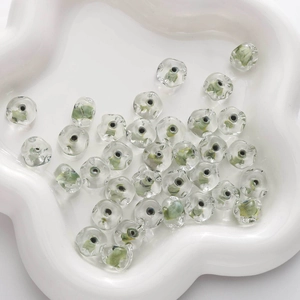Détail macro de perles en verre de 12x7mm avec motifs de vagues et volutes florales