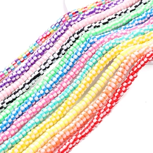 Primo piano di perle heishi in pasta polimerica a righe colorate in vari motivi