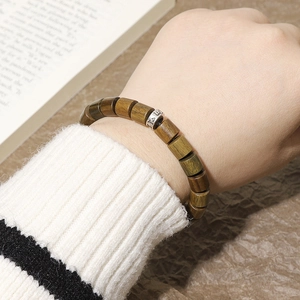 Detalle de pulsera de cuentas de madera marrón oscuro con separador de metal plateado