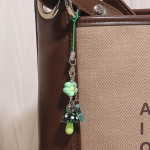 Détail macro d'une breloque de sac champignon et fleur verte avec pendentif lune bleu