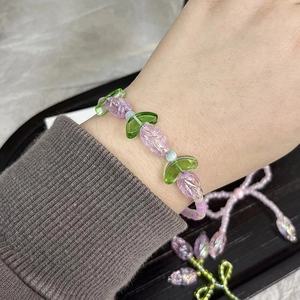Detail of tulip-shaped acrylic beads bracelet with purple petals and green leaves on wrist