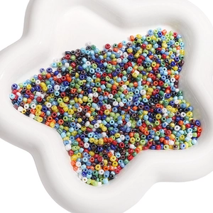 Perles de rocaille colorées de 2mm mélangées dans un bol en céramique blanc étoilé