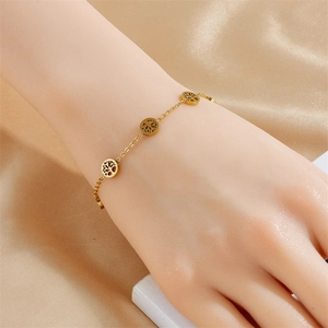 Golden Tree of Life charm bracelet in stainless steel worn on wrist with satin background