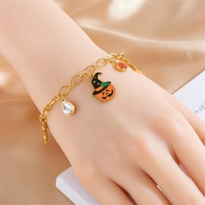 Bracciale dorato di Halloween con zucca, cappello da mago e cristalli su sfondo di seta