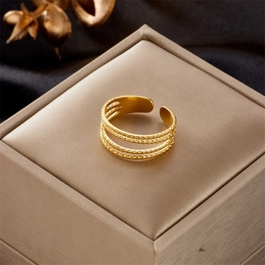 Detail of adjustable gold ring with triple-layered bands and beaded texture on box