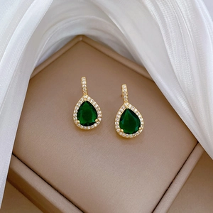 Detail of pear-cut emerald earrings with diamond halo in a luxury jewelry box