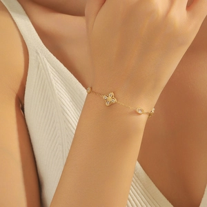 Élégant bracelet trèfle doré avec zircons blancs porté au poignet sur un mannequin