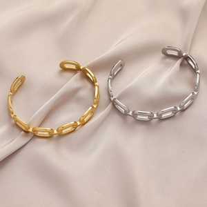 Polished gold and silver chain link open cuff bracelets on beige silk background