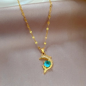 Elegante collana a delfino dorata con zircone blu su sfondo di seta color champagne