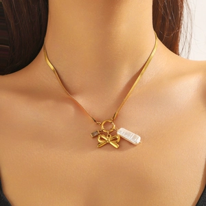 Dettaglio della collana a serpente dorata con fiocco e pendenti di perle sul collo