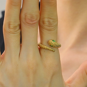 Elegante anillo de serpiente dorado con ojos de cristal verde y escamas en el dedo