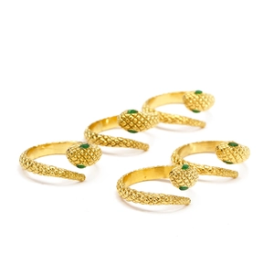 Detalle macro de anillos de serpiente dorados con ojos esmeralda y escamas grabadas