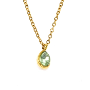 Détail d'un collier doré avec pendentif en zircone verte taille poire sur fond blanc pur
