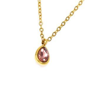 Détail macro d'un pendentif en zircone rose avec une finition dorée mate sur une chaîne