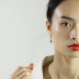 Élégantes créoles en or 18 carats avec zircons verts portées par un mannequin