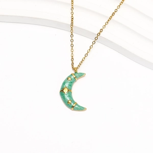 Detail of 18k gold moon pendant with emerald green enamel and gold star relief