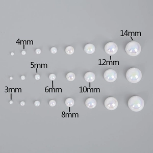 Vista piatta di mezze perle bianche iridescenti in misure da 3mm a 14mm per lavori fai-da-te