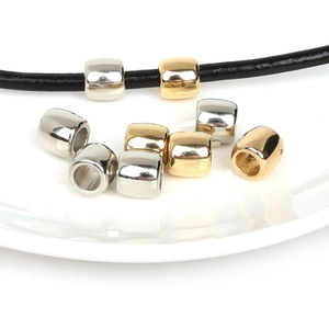 Golden and silver large hole barrel beads for DIY jewelry making on white ceramic background