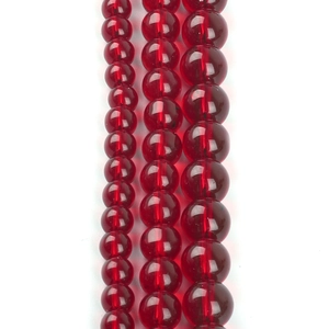 Detailed view of three sizes of round garnet red glass beads for DIY jewelry making