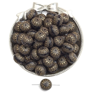 Macro shot of black acrylic beads with gold engraved heart patterns for DIY jewelry making