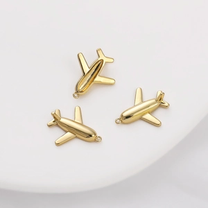 Detailed close-up of three 14K gold-plated airplane charms for DIY jewelry making and necklaces