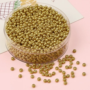 Vue détaillée de perles de rocaille dorées en boîte ronde sur un fond rose pastel