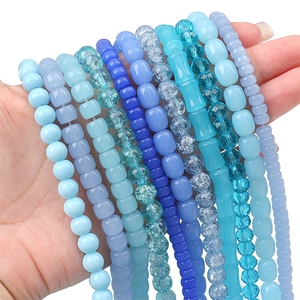Mix of blue glass beads in various shapes and sizes held in hand for DIY jewelry making